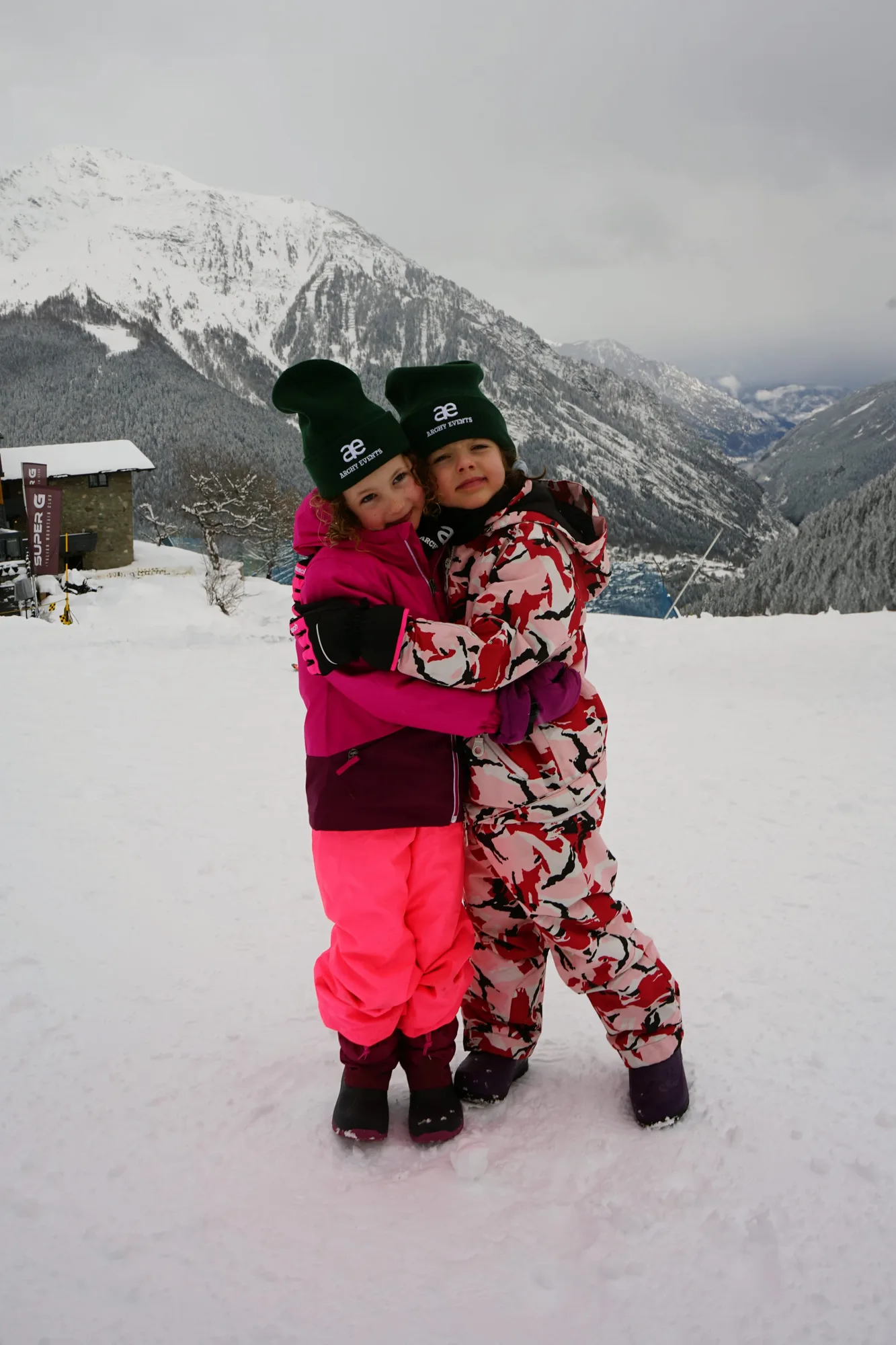 Two kids hugging on the slopes on a family ski week