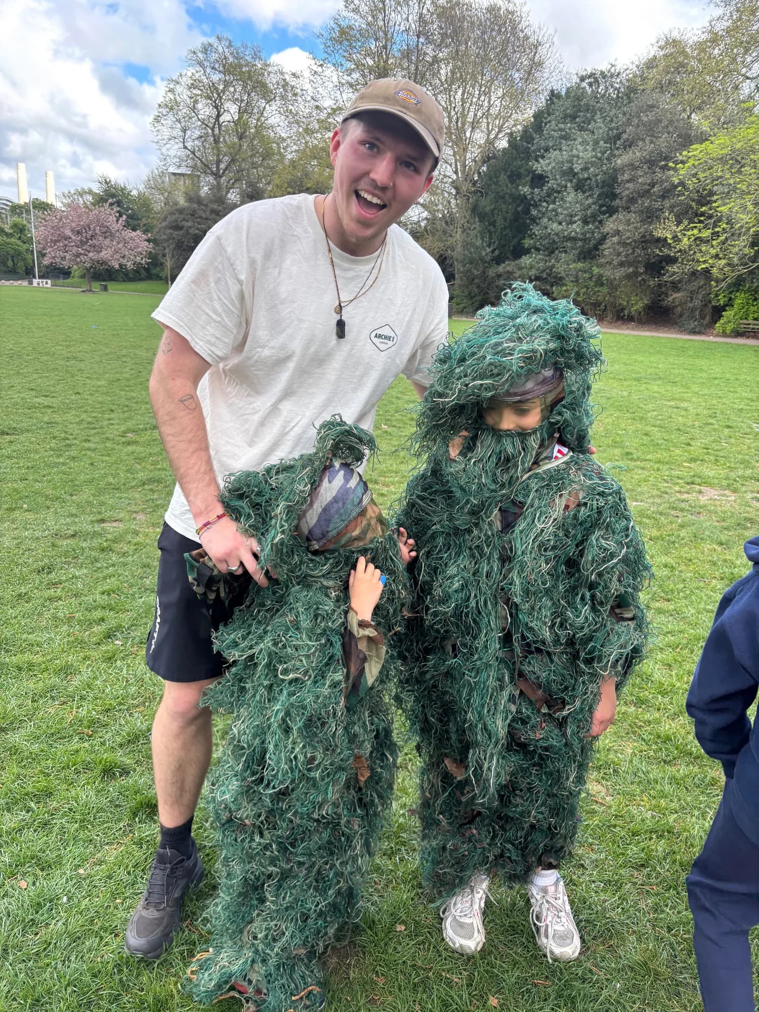 A camper in a full ghillie suit next to an Archie's leader