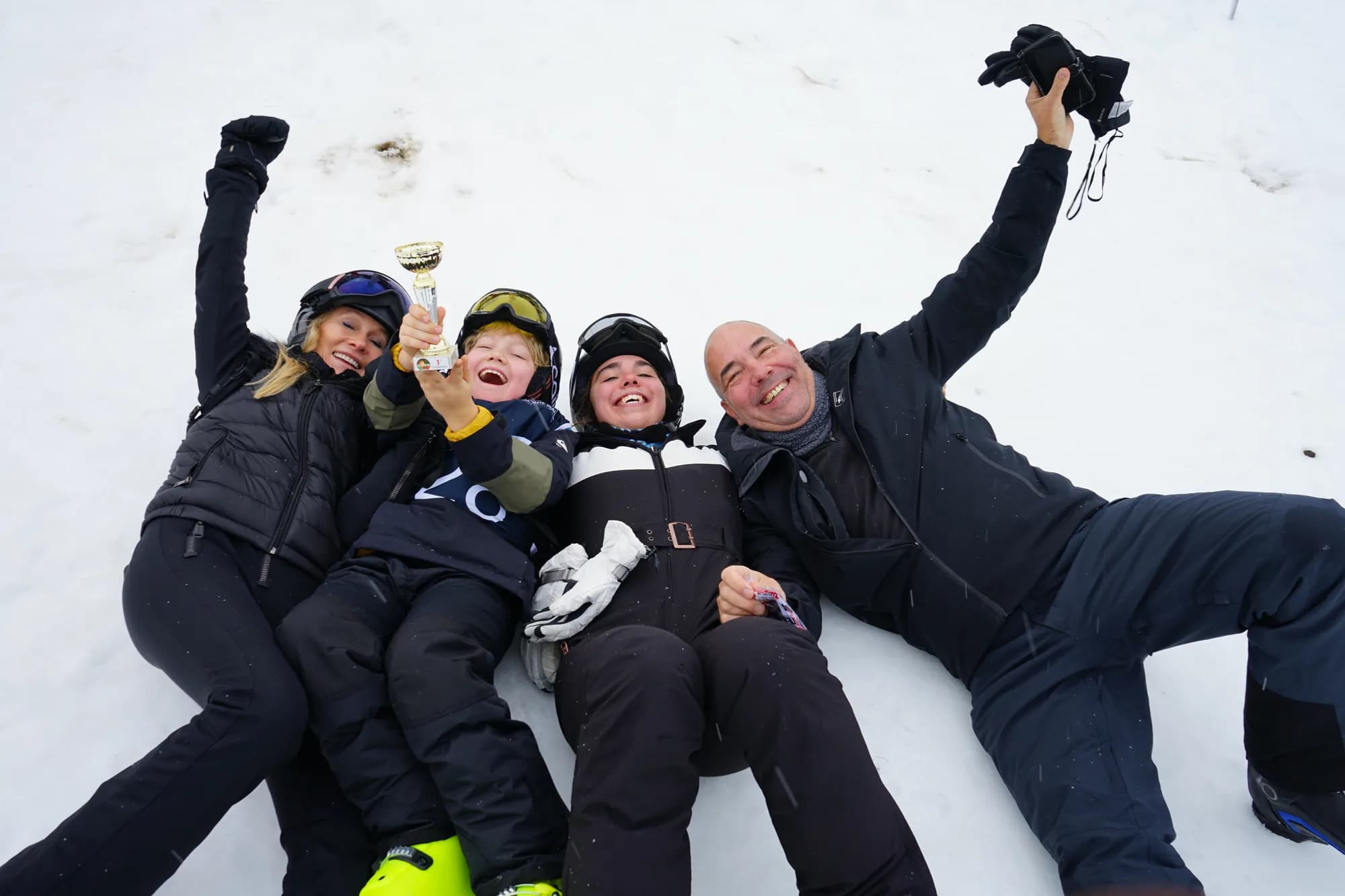 A family lying in the snow laughing on a ski week